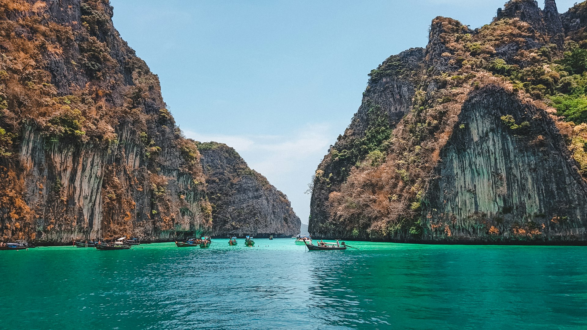boat on water near brown rock formation during daytime